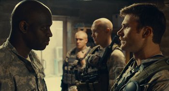 Movie still from “The Outpost” (2019), directed by Rod Lurie – A group of men standing next to each other in a room; Medium shot, Over the shoulder angle