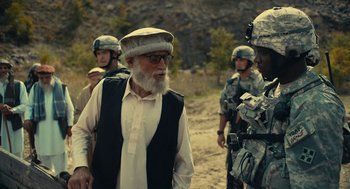 Movie still from “The Outpost” (2019), directed by Rod Lurie – An old man wearing a hat talking to a soldier; Medium shot, Over the shoulder angle