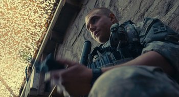 Movie still from “The Outpost” (2019), directed by Rod Lurie – A man sitting in front of a brick wall playing a video game; Close Up shot, Low angle