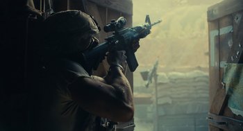 Movie still from “The Outpost” (2019), directed by Rod Lurie – A soldier is holding a rifle and aiming it; Medium shot, Low angle