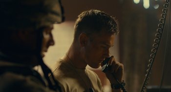 Movie still from “The Outpost” (2019), directed by Rod Lurie – A man talking on a cell phone next to another man; Close Up shot, Low angle