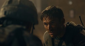 Movie still from “The Outpost” (2019), directed by Rod Lurie – A man with a helmet on talking to another man; Close Up shot, Over the shoulder angle