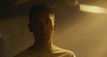 Movie still from “The Outpost” (2019), directed by Rod Lurie – A young man with a beard is looking into the distance; Close Up shot, Low angle