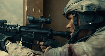 Movie still from “The Outpost” (2019), directed by Rod Lurie – A soldier is holding a rifle and aiming it; Close Up shot, Over the shoulder angle