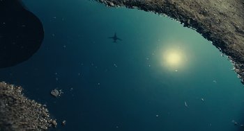 Movie still from “The Outpost” (2019), directed by Rod Lurie – A view of a plane flying over a body of water; Extreme Wide shot, Overhead angle