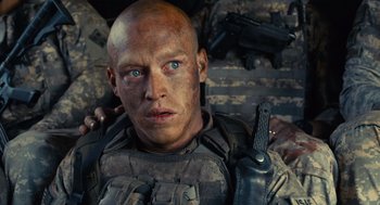 Movie still from “The Outpost” (2019), directed by Rod Lurie – A man with a gun in his hand and a rifle in his other hand; Close Up shot, Over the shoulder angle