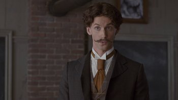 Movie still from “Anne with an E” (2017), created by Moira Walley-Beckett – A man in a suit and tie with a mustache; Close Up shot, Low angle
