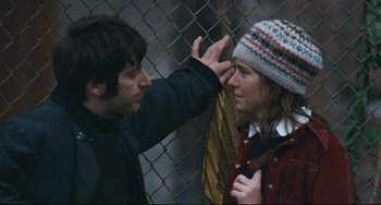Movie still from “The Panic in Needle Park” (1971), directed by Jerry Schatzberg – A man and a woman standing next to each other near a chain link fence; Close Up shot, Over the shoulder angle