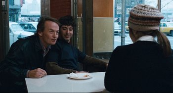 Movie still from “The Panic in Needle Park” (1971), directed by Jerry Schatzberg – A group of people sitting at a table with food; Medium shot, Over the shoulder angle
