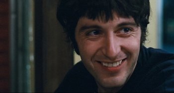 Movie still from “The Panic in Needle Park” (1971), directed by Jerry Schatzberg – A man smiling for the camera; Close Up shot, Low angle