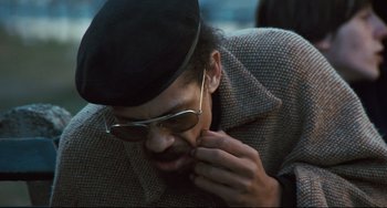 Movie still from “The Panic in Needle Park” (1971), directed by Jerry Schatzberg – A man in a hat and glasses is looking down; Close Up shot, Low angle