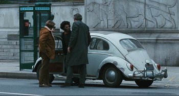 Movie still from “The Panic in Needle Park” (1971), directed by Jerry Schatzberg – Three people standing next to an old vw beetle car; Wide shot, High angle