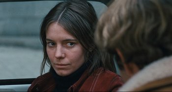 Movie still from “The Panic in Needle Park” (1971), directed by Jerry Schatzberg – A young woman with long brown hair wearing a red jacket; Close Up shot, Over the shoulder angle