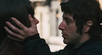 Movie still from “The Panic in Needle Park” (1971), directed by Jerry Schatzberg – A man with his hand to his ear while another man with his hand to his ear looks at him; Close Up shot, Over the shoulder angle