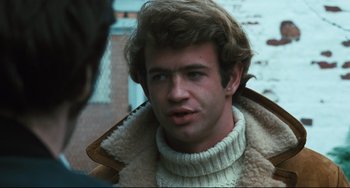 Movie still from “The Panic in Needle Park” (1971), directed by Jerry Schatzberg – A young man wearing a white sweater and a brown jacket; Close Up shot, Over the shoulder angle