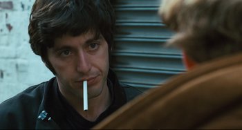 Movie still from “The Panic in Needle Park” (1971), directed by Jerry Schatzberg – A man smoking a cigarette in front of another man; Close Up shot, Over the shoulder angle