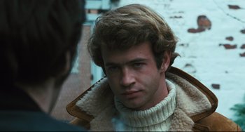 Movie still from “The Panic in Needle Park” (1971), directed by Jerry Schatzberg – A young man wearing a sweater and a jacket; Close Up shot, Over the shoulder angle