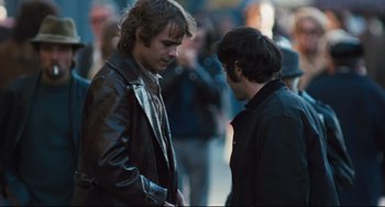 Movie still from “The Panic in Needle Park” (1971), directed by Jerry Schatzberg – Two men are standing in the street talking to each other; Medium shot, Over the shoulder angle