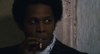 Movie still from “The Panic in Needle Park” (1971), directed by Jerry Schatzberg – A man smoking a cigarette while wearing a white neck tie; Close Up shot, Over the shoulder angle