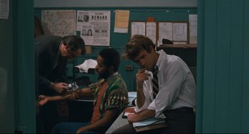 Movie still from “The Panic in Needle Park” (1971), directed by Jerry Schatzberg – A man in a tie sitting next to another man in a tie; Medium shot, Over the shoulder angle