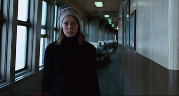 Movie still from “The Panic in Needle Park” (1971), directed by Jerry Schatzberg – A woman in a black sweater and a hat is standing in a hallway; Medium shot, Low angle