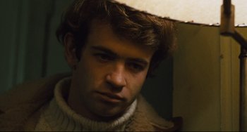 Movie still from “The Panic in Needle Park” (1971), directed by Jerry Schatzberg – A young man with brown curly hair wearing a white hat; Close Up shot, Low angle