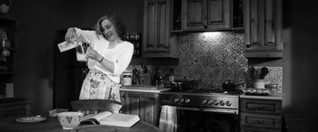Movie still from “The Party” (2017), directed by Sally Potter – A woman standing in a kitchen holding a cell phone; Medium shot, Low angle