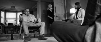 Movie still from “The Party” (2017), directed by Sally Potter – A man and a woman are standing in front of a door; Wide shot, Over the shoulder angle