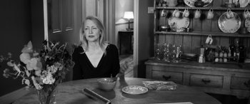 Movie still from “The Party” (2017), directed by Sally Potter – A woman sitting at a table with a bowl of food; Medium shot, Over the shoulder angle