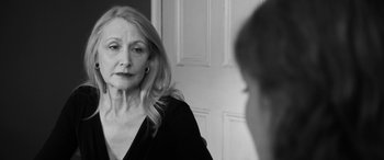 Movie still from “The Party” (2017), directed by Sally Potter – An older woman looking at a young man in a mirror; Close Up shot, Over the shoulder angle