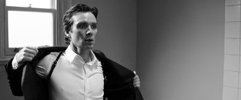 Movie still from “The Party” (2017), directed by Sally Potter – A black and white photo of a man holding a jacket; Close Up shot, Low angle