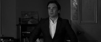 Movie still from “The Party” (2017), directed by Sally Potter – Black and white photograph of a man in a suit; Medium shot, Low angle