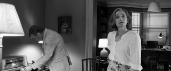 Movie still from “The Party” (2017), directed by Sally Potter – A woman standing in front of a man in front of a mirror; Medium shot, Over the shoulder angle