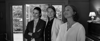 Movie still from “The Party” (2017), directed by Sally Potter – A group of women standing next to each other in front of a window; Medium shot, Low angle