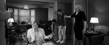 Movie still from “The Party” (2017), directed by Sally Potter – A group of people standing around a living room; Wide shot, Over the shoulder angle