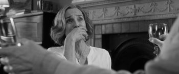 Movie still from “The Party” (2017), directed by Sally Potter – A black - and - white photo of a woman with her hand to her mouth; Close Up shot, Over the shoulder angle