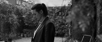 Movie still from “The Party” (2017), directed by Sally Potter – Black and white photograph of a woman in a suit; Medium shot, Low angle