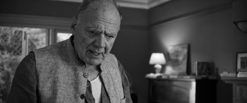 Movie still from “The Party” (2017), directed by Sally Potter – An older man is looking at the camera; Close Up shot, Over the shoulder angle