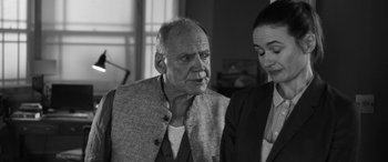 Movie still from “The Party” (2017), directed by Sally Potter – An older man and a younger woman standing next to each other; Close Up shot, Over the shoulder angle