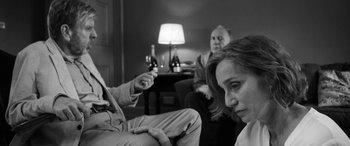Movie still from “The Party” (2017), directed by Sally Potter – A man and a woman sitting on a couch with a wine glass in front of them; Medium shot, Over the shoulder angle