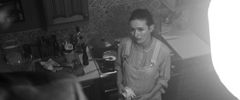 Movie still from “The Party” (2017), directed by Sally Potter – A woman standing in front of a stove holding a pan; Medium shot, High angle