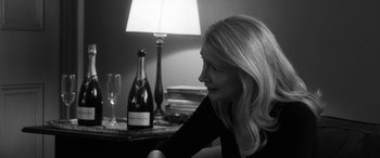 Movie still from “The Party” (2017), directed by Sally Potter – A black and white photo of a woman sitting in front of a bottle of wine; Close Up shot, Over the shoulder angle