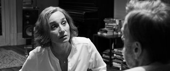 Movie still from “The Party” (2017), directed by Sally Potter – A black and white photo of a woman in front of a stack of books; Close Up shot, Over the shoulder angle