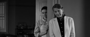 Movie still from “The Party” (2017), directed by Sally Potter – A woman standing next to another woman in front of a mirror; Medium shot, Over the shoulder angle