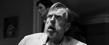 Movie still from “The Party” (2017), directed by Sally Potter – An older man with a goatee stares into the distance; Close Up shot, Over the shoulder angle