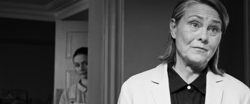 Movie still from “The Party” (2017), directed by Sally Potter – A woman standing in front of a mirror wearing a white jacket; Close Up shot, Over the shoulder angle