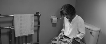 Movie still from “The Party” (2017), directed by Sally Potter – A woman sitting in a bathroom next to a roll of toilet paper; Medium shot, Over the shoulder angle