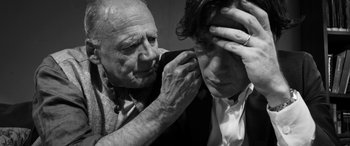 Movie still from “The Party” (2017), directed by Sally Potter – An older man and a younger man are fixing each other's hair; Close Up shot, Over the shoulder angle