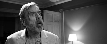 Movie still from “The Party” (2017), directed by Sally Potter – An older man with a surprised look on his face; Close Up shot, Over the shoulder angle