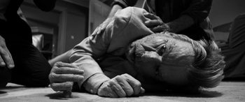 Movie still from “The Party” (2017), directed by Sally Potter – A man laying on the ground with his head in his hands; Close Up shot, Overhead angle
